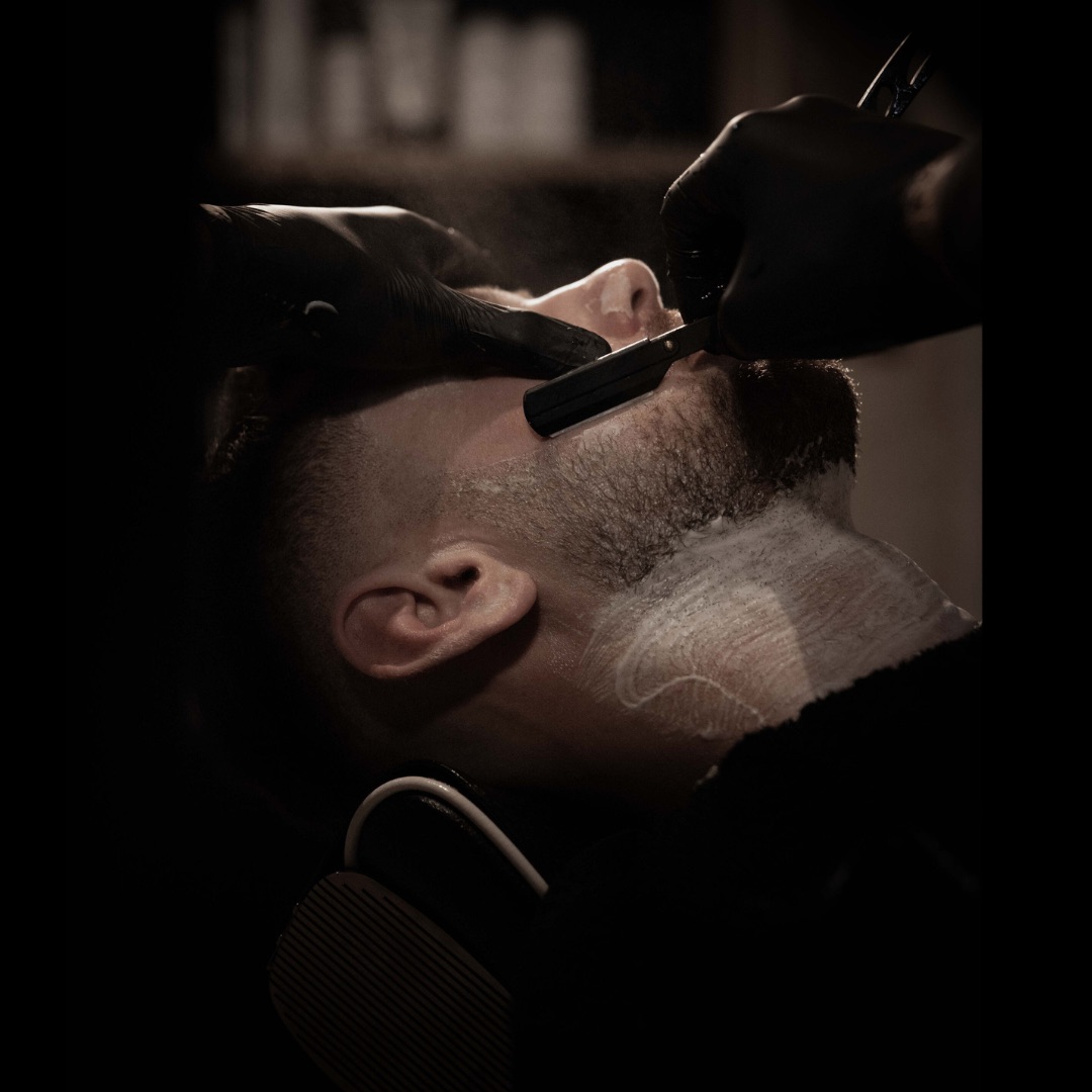 A barber performing a precise straight-razor finish